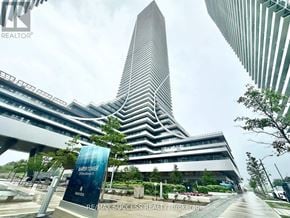 Toronto (Mimico) condo for rent - A tall building with a pointed top is surrounded by other buildings.