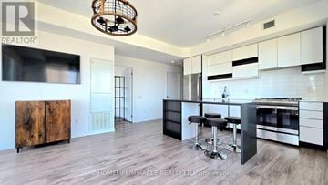 Mississauga (City Centre) condo for rent - A modern kitchen with white cabinets and a wooden cabinet.