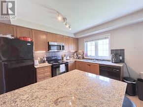 Hamilton (Hamilton Beach) townhouse for rent - A kitchen with a granite countertop and wooden cabinets.