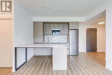Mississauga (Central Erin Mills) condo for rent - A kitchen with a white island and a refrigerator.