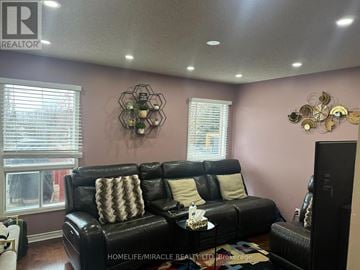 Mississauga (Meadowvale) apartment for rent - A living room with a black leather couch and a television.