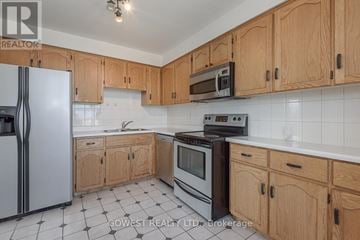 Hamilton (Stinson) condo for rent - A kitchen with wooden cabinets and a black and white tiled floor.