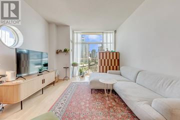 Toronto (Waterfront Communities) condo for rent - A living room with a white couch and a wooden entertainment center.