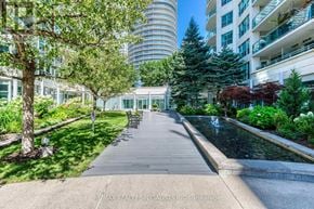 Toronto (Waterfront Communities) condo for rent - A walkway with a water feature and trees in the foreground with apartment buildings in the background.