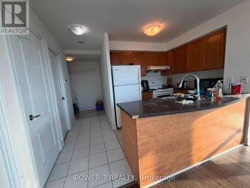 Toronto (Bendale) condo for rent - A kitchen with wooden cabinets and a black countertop.