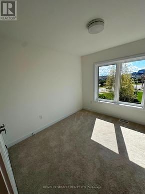 Guelph (Clairfields/Hanlon Business Park) townhouse for rent - A room with a window showing a view of trees and a car outside.