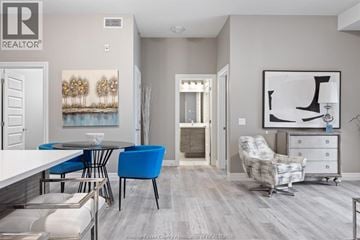Tecumseh condo for rent - A living room with a blue chair and a white table.