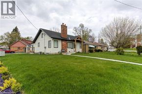 Kitchener apartment for rent - A house with a red roof and a chimney is surrounded by a green lawn.