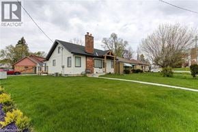 Kitchener apartment for rent - A house with a red roof and a chimney is surrounded by a green lawn.