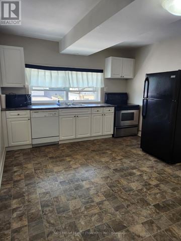 Niagara Falls (Clifton Hill) apartment for rent - A kitchen with black appliances and white cabinets.