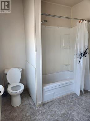 Niagara Falls (Clifton Hill) apartment for rent - A white toilet is in a bathroom with a white shower curtain.