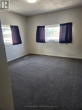 Niagara Falls (Clifton Hill) apartment for rent - A room with grey carpet and two windows with purple curtains.