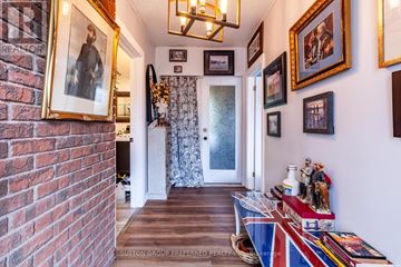 Aylmer apartment for rent - A hallway with a brick wall on the left and a series of framed pictures on the wall.