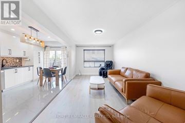 Oshawa (Taunton) townhouse for rent - A living room with a brown leather couch and a dining table with chairs.