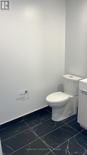 Burlington (Brant) condo for rent - A white toilet in a bathroom with black tiles.