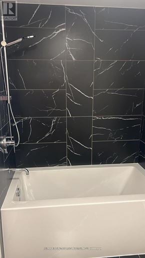 Burlington (Brant) condo for rent - A white bathtub in a bathroom with black marble tiles.
