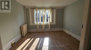 Ottawa fourplex for rent - A room with wooden floors and a window with curtains.