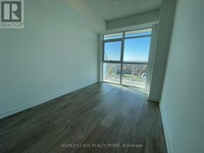 Toronto (Mimico) condo for rent - A room with wooden flooring and a large window overlooking a cityscape.