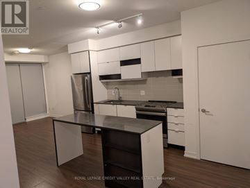 Mississauga (City Centre) condo for rent - A kitchen with white cabinets and a black countertop.
