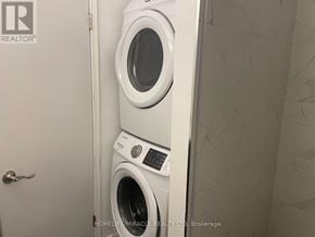 Kitchener apartment for rent - A white washing machine is stacked on top of another in a small bathroom.