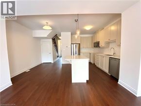 Beamsville townhouse for rent - A large, empty kitchen with white cabinets and a wooden floor.