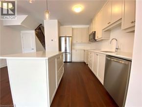 Beamsville townhouse for rent - A kitchen with white cabinets and a wooden floor.