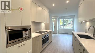 North Vancouver townhouse for rent - A modern kitchen with white cabinets and stainless steel appliances.