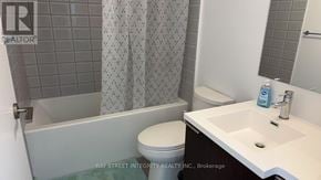 Toronto (Kensington-Chinatown) condo for rent - A bathroom with a toilet, sink, and shower curtain.