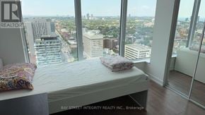 Toronto (Kensington-Chinatown) condo for rent - A bedroom with a large window overlooking a cityscape.