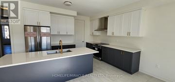 Adjala-Tosorontio (Colgan) apartment for rent - A kitchen with white cabinets and a black island.