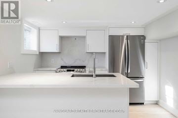 Toronto (Bedford Park-Nortown) apartment for rent - A modern kitchen with white cabinets and a stainless steel refrigerator.