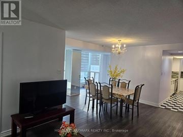 Toronto (Dorset Park) condo for rent - A living room with a television and a dining table.
