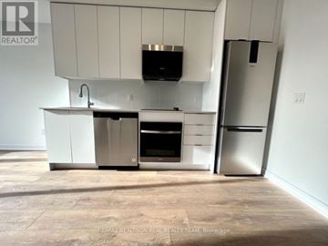 Vaughan (Concord) condo for rent - A kitchen with white cabinets and appliances in a room with a tiled floor.