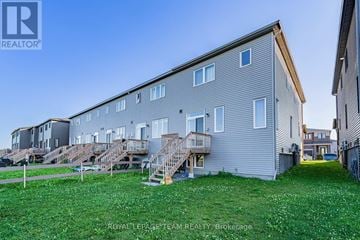 Ottawa townhouse for rent - A large grey building with a grassy area in front and a clear blue sky above.