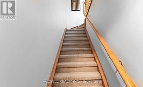 Toronto (Long Branch) townhouse for rent - A staircase with a beige carpet and wooden handrails.