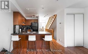 Toronto (Long Branch) townhouse for rent - A modern kitchen with a bar stool and a staircase in the background.