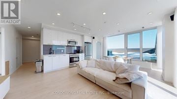 Toronto (Weston-Pellam Park) condo for rent - A spacious living room with a large couch and a kitchen area in the background.