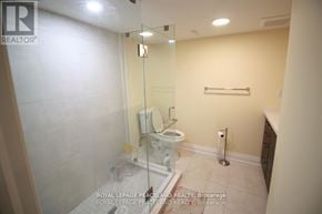 Oakville (Ga Glen Abbey) apartment for rent - A white toilet in a small bathroom with a glass shower door.