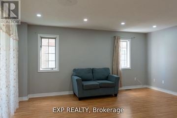 Brampton (Sandringham-Wellington) townhouse for rent - A living room with a grey couch and two windows.