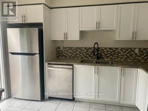 Brantford townhouse for rent - A kitchen with white cabinets and a stainless steel refrigerator.