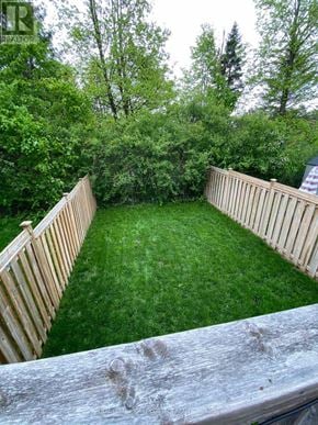 Barrie (Georgian Drive) townhouse for rent - A backyard with a wooden fence and a green lawn.