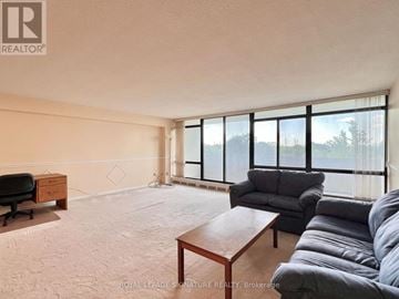 Toronto (Don Valley Village) condo for rent - A living room with a grey couch and a wooden coffee table.