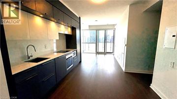 Toronto condo for rent - A modern kitchen with dark wood floors and a large window.