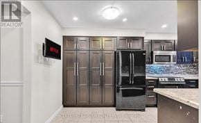 Hamilton (Stoney Creek) apartment for rent - A kitchen with a black fridge and a TV mounted on the wall.