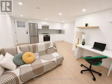 Toronto (Dovercourt-Wallace Emerson-Junction) apartment for rent - A living room with a couch, a desk, and a kitchen area in the background.