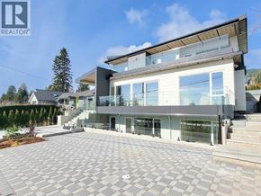 West Vancouver apartment for rent - A modern house with a large glass front and a grey tiled driveway.