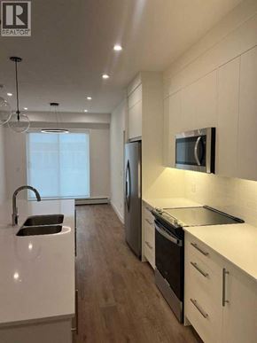 Calgary apartment for rent - A modern kitchen with white cabinets and stainless steel appliances.