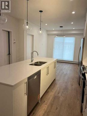 Calgary apartment for rent - A modern kitchen with a sink, cabinets, and a refrigerator.