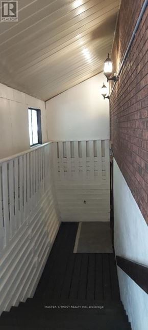 Barrie (Codrington) apartment for rent - A long, narrow hallway with a brick wall on the side and a wooden ceiling.