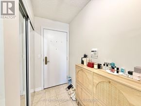 Toronto (Willowdale East) condo for rent - A room with a white door and a wooden cabinet with various items on top.